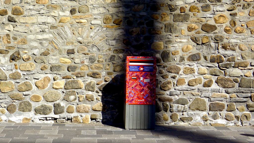A Canada Post mailbox against a stone wall